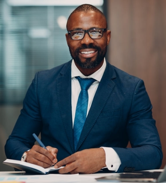 Portrait smiling african american businessman in blue suit sit at table for meeting in office with notebook with pen and laptop