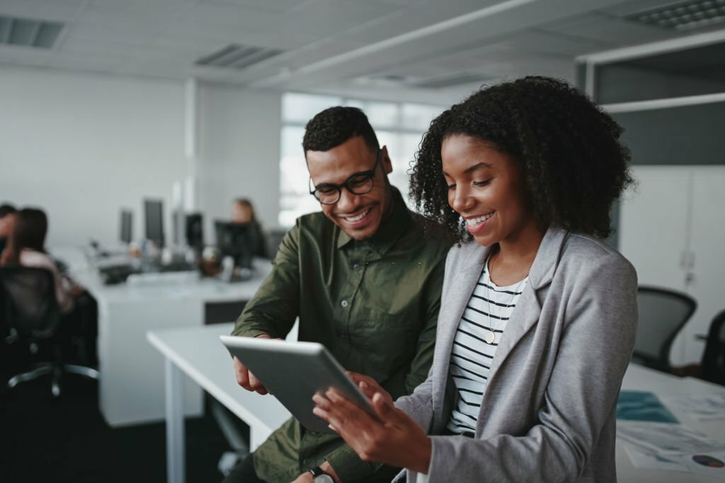 Professional young businesspeople using tablet computer smiling in office